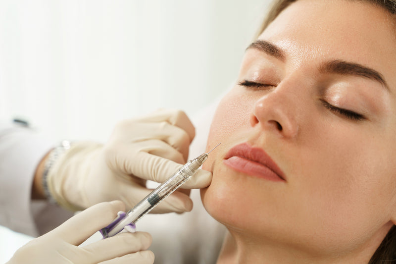 A woman receiving a filler injection near her mouth