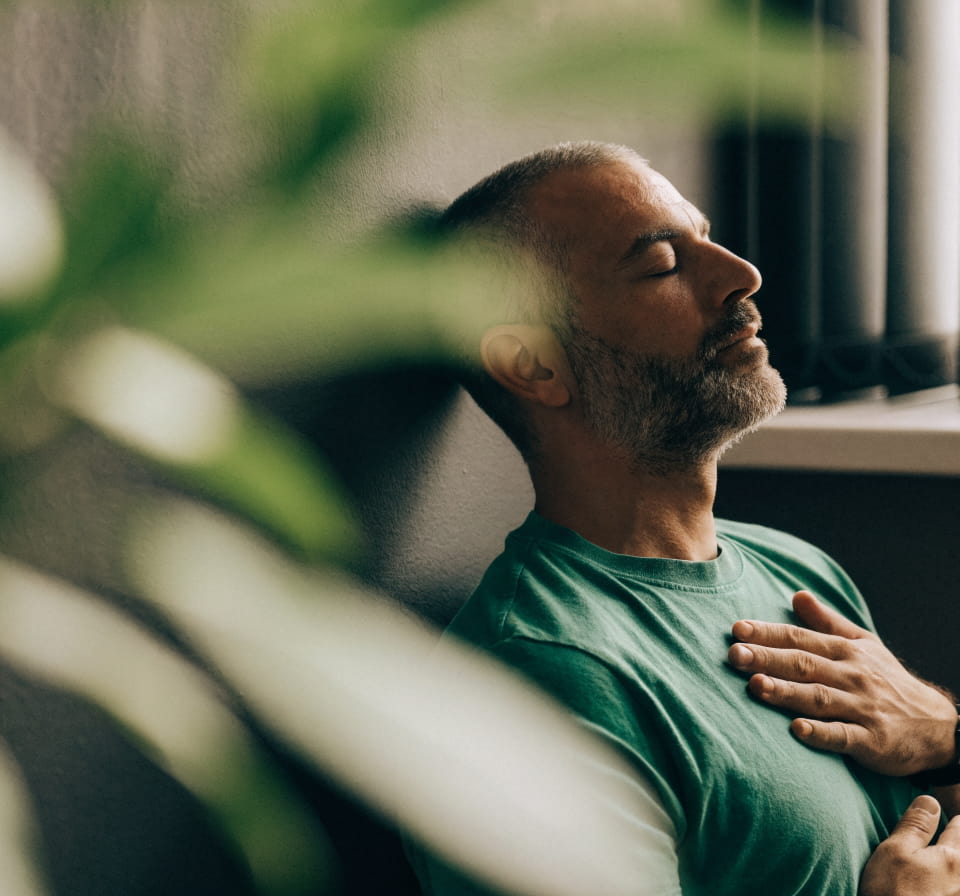 A man breathing deeply with his eyes closed and a hand on his chest